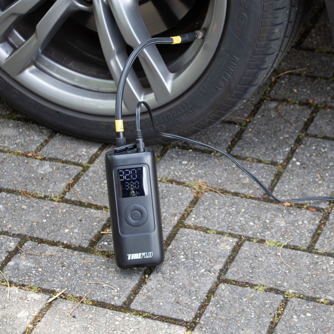 Digital Truflo Max electronic pump connected to a car tire on a paved surface.