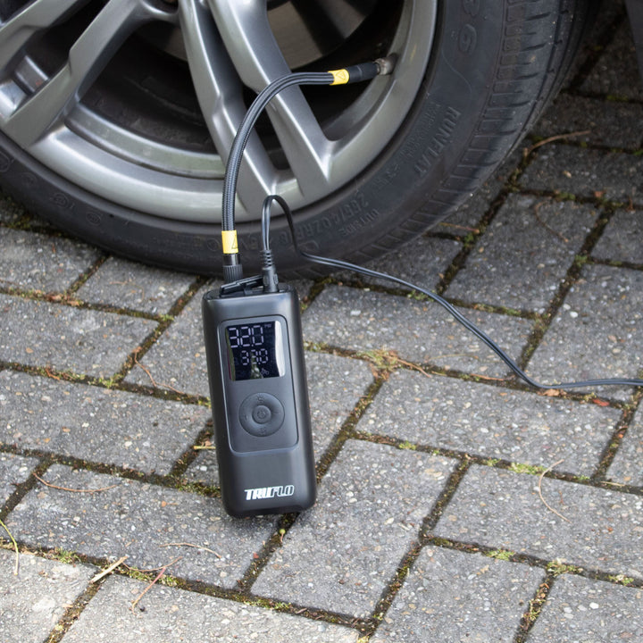 Digital Truflo Max electronic pump connected to a car tire on a paved surface.