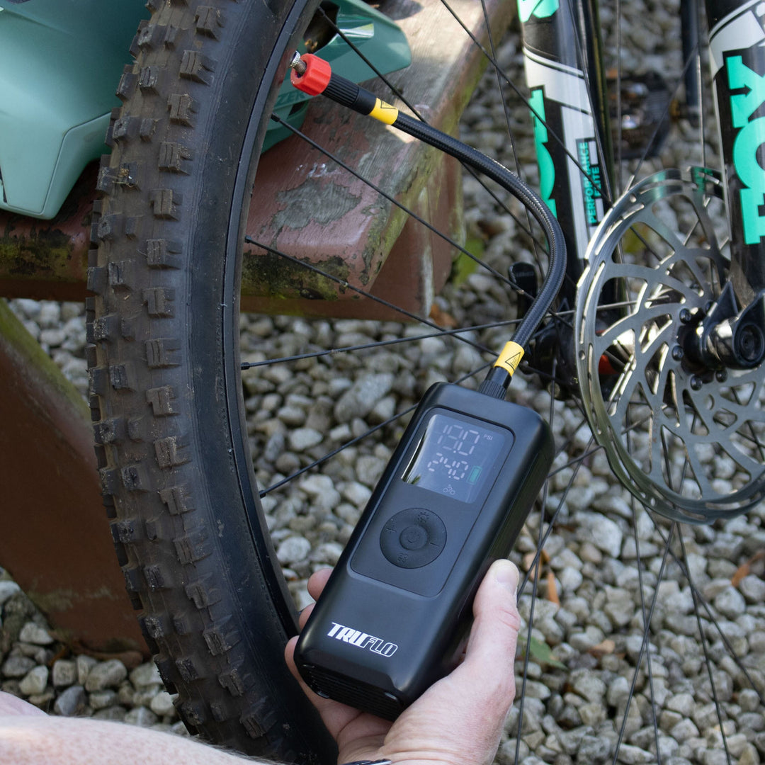 Person using a Truflo digital pump on a mountain bike tyres outdoors.